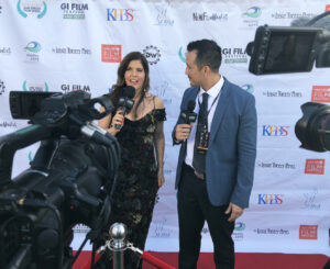 A man and woman are being interviewed on the red carpet.