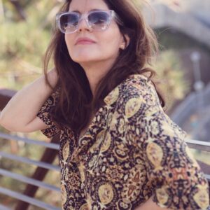 A woman wearing sunglasses and a brown floral shirt.