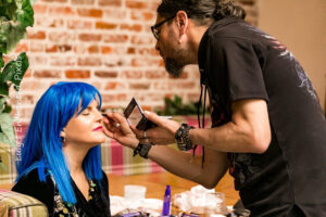 A man is putting makeup on a woman 's face.
