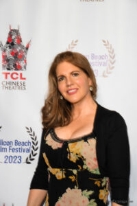 A woman in black shirt and white dress standing on red carpet.